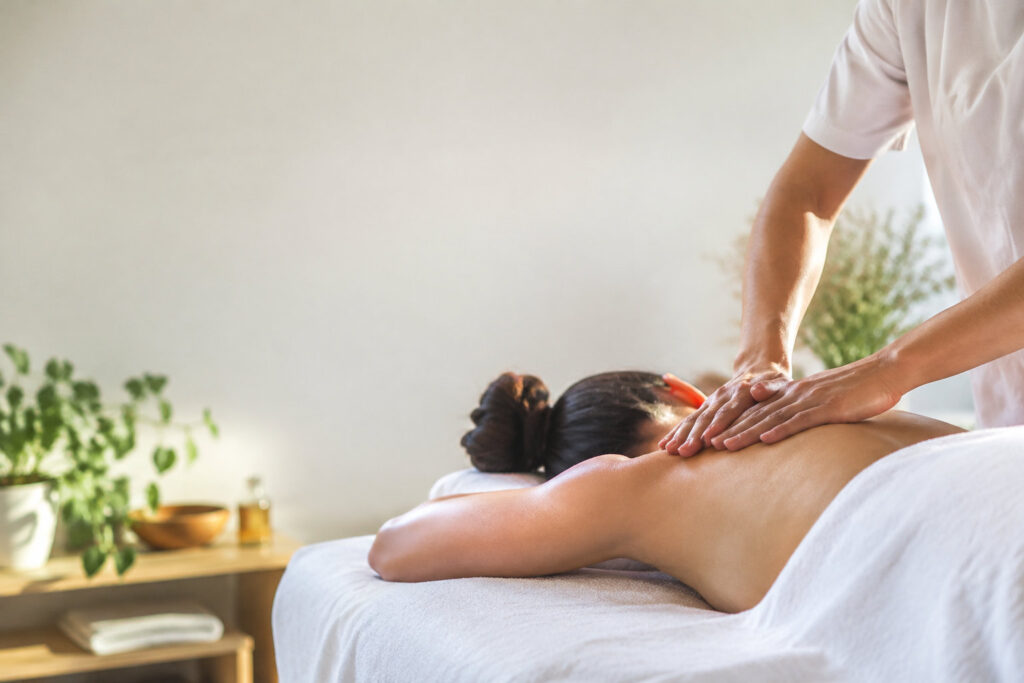 Une femme allongée sur une table de massage reçoit un soin thérapeutique du dos dans un cabinet apaisant.